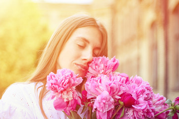 Fototapeta premium beautiful girl, no makeup, natural beauty, feminism. woman in a white dress, crosswise with a bouquet of peonies
