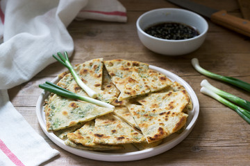 Homemade appetizing scallion pancakes and a bunch of green onions. Rustic style.