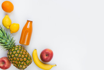Top view of various fruits and a bottle of freshly squeezed  multivitamin juice on a white background. Copy space. Flat lay.