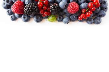 Mix berries on a white background. Ripe blueberries, red currants, backberries, gooseberries and raspberries on white background. Top view. Fruits and berries at border with copy space for text.