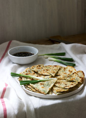 Homemade appetizing scallion pancakes and a bunch of green onions. Rustic style.