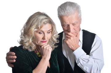 Portrait of sad senior couple hugging on white background