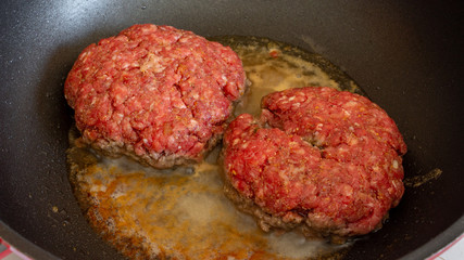 greasy burgers cooking in non stick pan