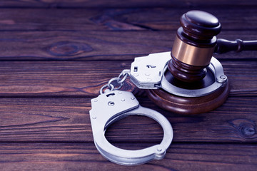 the judge's gavel, handcuffs on wooden background.