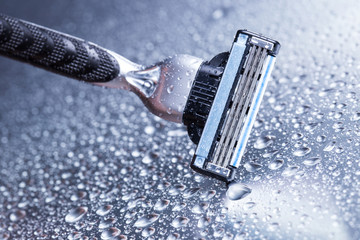 Razor close-up with water drops on a gray background.