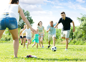 Parents with children playing football on outdoor