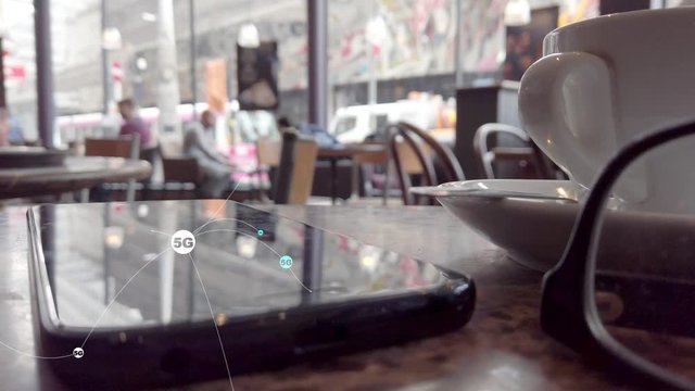 Coffee shop 5g network.  Mobile phone on a coffee shop table composited with a 5g network diagram.