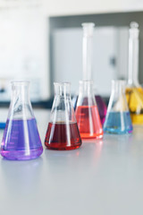 Chemical laboratory flask with blue purple-pink liquid stand on the table