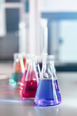 Chemical laboratory flask with blue purple-pink liquid stand on the table
