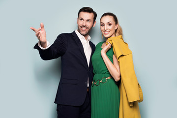 Joyful couple, elegantly dressed, standing on a blue background