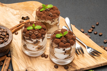 Classic tiramisu dessert in a glass on dark concrete background