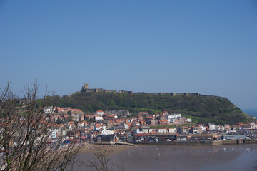 Fototapeta na wymiar View of castle on hill above town in Scarborough, UK on a clear blue sky sunny day