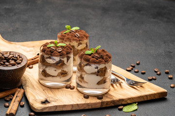Classic tiramisu dessert in a glass on dark concrete background
