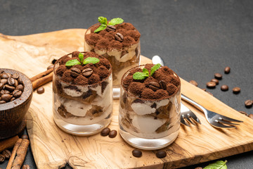 Classic tiramisu dessert in a glass on dark concrete background