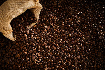 Dark roasted coffee beans spilling from a sack