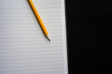 image of a notebooks and pencil on black background, close-up, selective focus