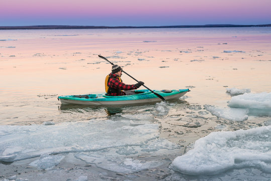 Man navigates in kayak alone on icy Ontario winter lake
