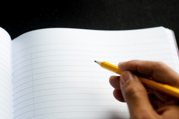image of a notebooks and pencil on black background, close-up, selective focus
