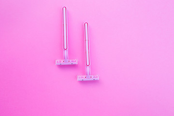 Two women's razors pink color on an isolated pink background.