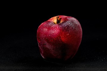 fresh and delicious red apple isolated against black background, with water droplets on the apple, selective focus