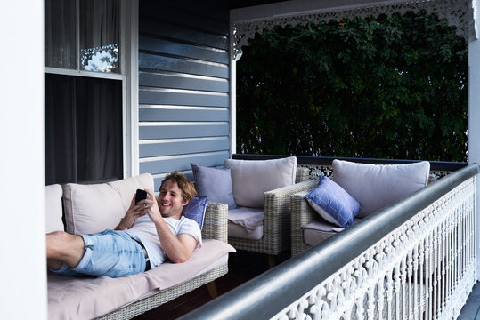 Aussie using smartphone at home on the lounge in a relaxed position.