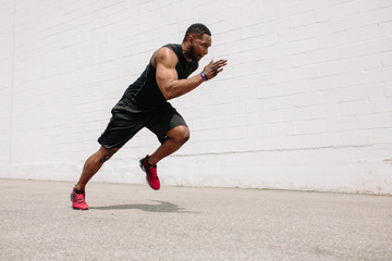 Fit athlete practicing sprints and jumps in a parking lot