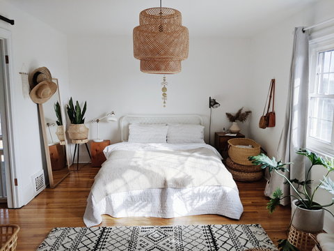 Bedroom setup with large mirror, snake plant and sun hats with wicker light