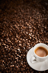 Cup of espresso coffee on roasted bean background