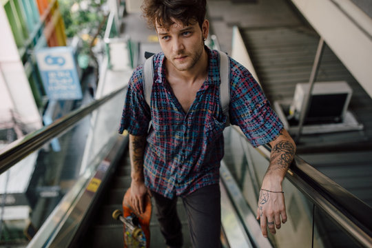 Young skater using escalator stairs downtown