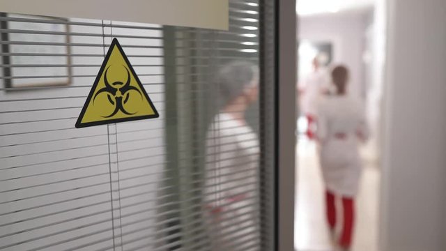 People working in laboratory. Biohazard symbol sign of biological threat alert on the lab entrance door