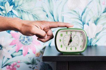 man turning off a retro alarm clock