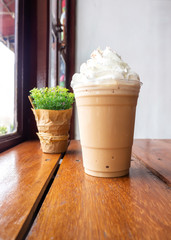 Cappuccino blend in plastic cup. Served on wooden table in cafe. Favorite menu of caffeine beverage.