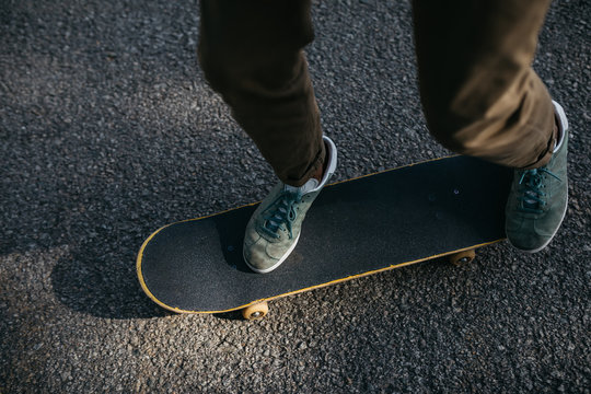 Crop skateboarder riding on street