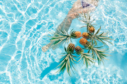 Woman's legs near floating pineapple