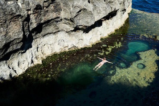 Traveler swimming relaxed at natural pool in summer.
