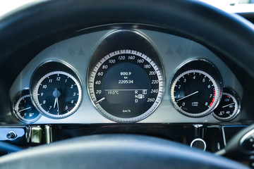 Car dashboard with speedometer, tachometer, clock, fuel tank gauge, oil temperature and display with on-board computer and black odometer with white arrows and divisions. Auto service industry.