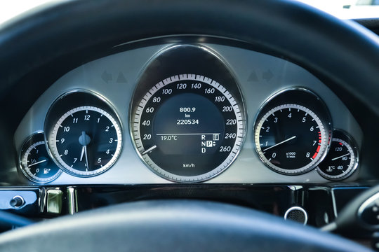 Car dashboard with speedometer, tachometer, clock, fuel tank gauge, oil temperature and display with on-board computer and black odometer with white arrows and divisions. Auto service industry.