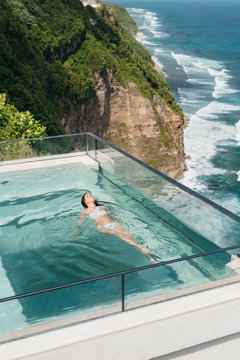 Woman Relaxing In A Infinity Pool On A Edge Of Cliff.