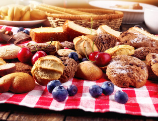 Cookies biscuit with blueberry. Chocolate bake and cherry cupcake with cup tea or coffee and tier stand on kitchen gingham checkered cotton fabric. Lunch in inexpensive cafe.