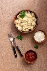 Russian food pelmeni meat dumplings with sour cream and tomato sauce. Top view, flat lay