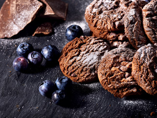 Serving food on slate onto wooden table. Oatmeal cookies biscuit with blueberry on picnic dark tiles countrylike. Chocolate chip cookies tied with string. Dessert in cafe.