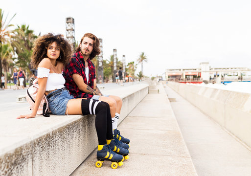 Beautiful young couple relaxing after skating in the street.