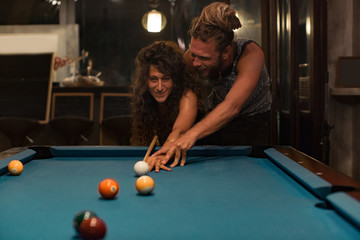 Happy couple playing pool in a bar