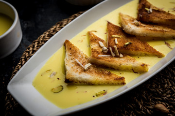 shahi tukra/tukda or Double ka meetha is a bread pudding Indian sweet of fried bread slices soaked in rabid or sweet saffron milk garnished with dry fruits, selective focus