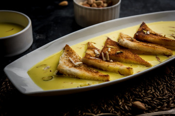 shahi tukra/tukda or Double ka meetha is a bread pudding Indian sweet of fried bread slices soaked in rabid or sweet saffron milk garnished with dry fruits, selective focus