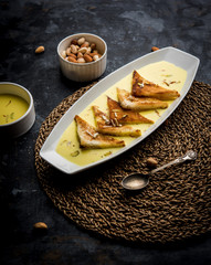 shahi tukra/tukda or Double ka meetha is a bread pudding Indian sweet of fried bread slices soaked in rabid or sweet saffron milk garnished with dry fruits, selective focus