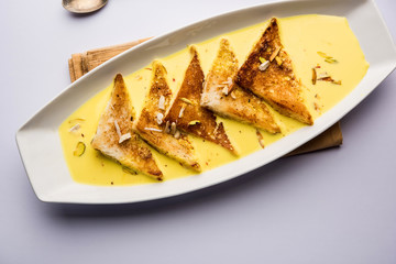 shahi tukra/tukda or Double ka meetha is a bread pudding Indian sweet of fried bread slices soaked in rabid or sweet saffron milk garnished with dry fruits, selective focus