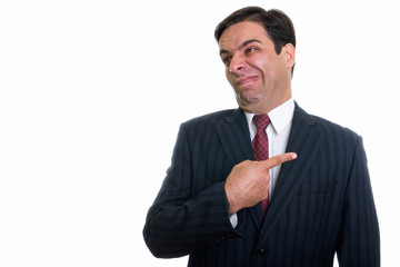Studio shot of young Persian businessman looking disgusted while