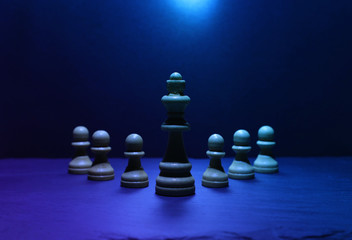 Wooden chess figures under dark and dramatic lighting