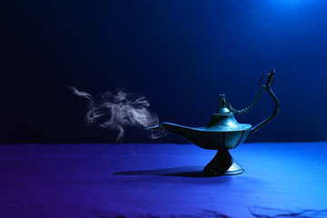 Image of magical mysterious aladdin lamp with smoke. Dark background and dramatic light